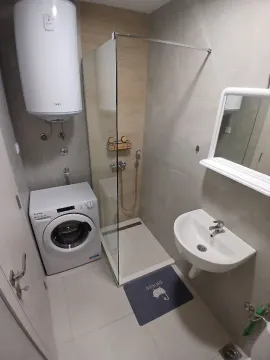 Smaller bathroom with a shower cabin, washbasin, washing machine, and water heater. - image 7