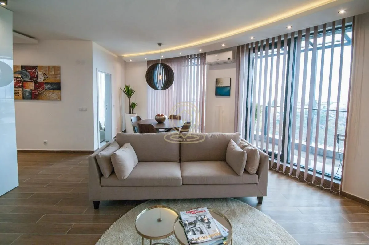 Living room with sofa, dining area and large windows.
