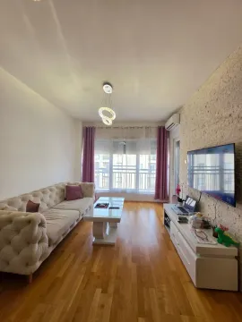 Living room with a sofa, TV, and a coffee table by the window. - image 2