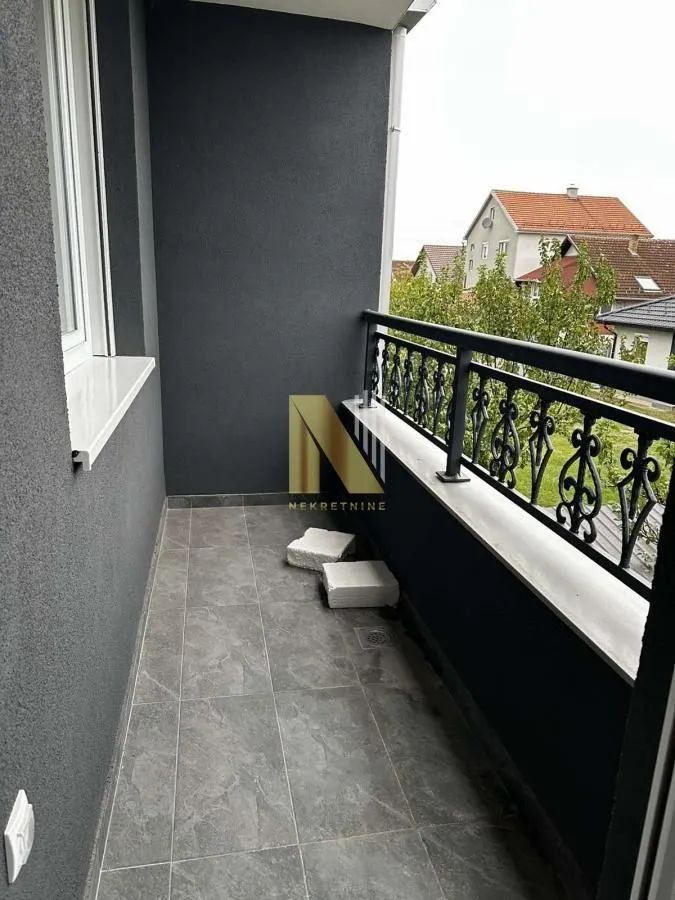 Pogled na prostrani i uređeni balkonski prostor sa metalnom ogradom.
