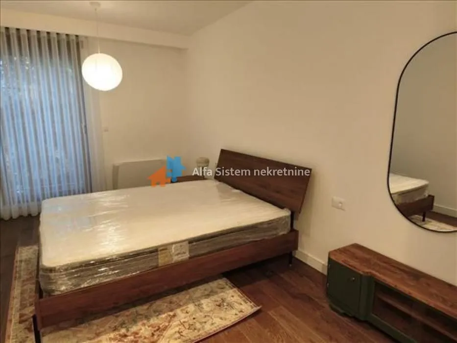 Furnished bedroom with a double bed, chest of drawers, and a mirror.