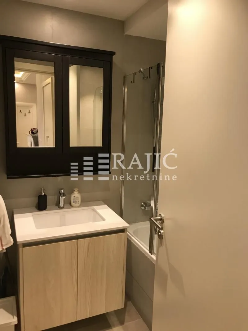 Small bathroom with a vanity, cabinet, and bathtub.
