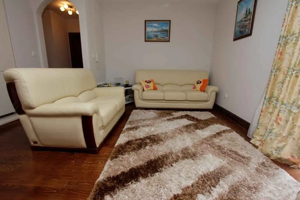 Living room with leather sofas and a decorative rug.