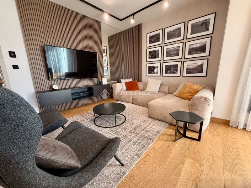 Modern and bright living room with a sofa, TV, and decorative wall panels.