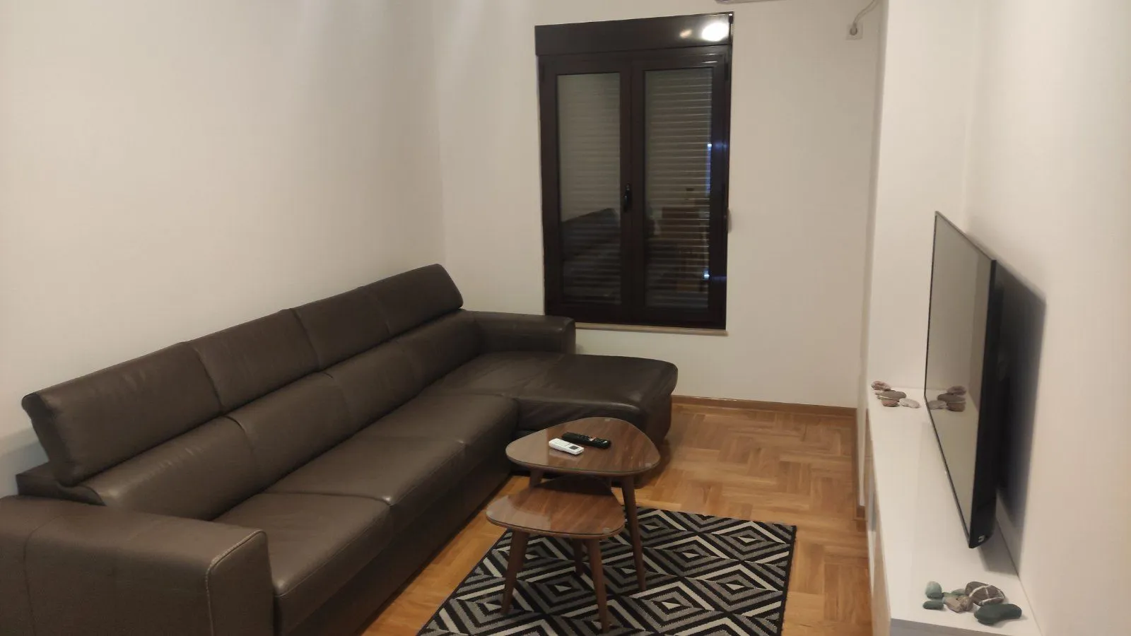 Living room with a leather sofa, small coffee table, and a wall-mounted TV.
