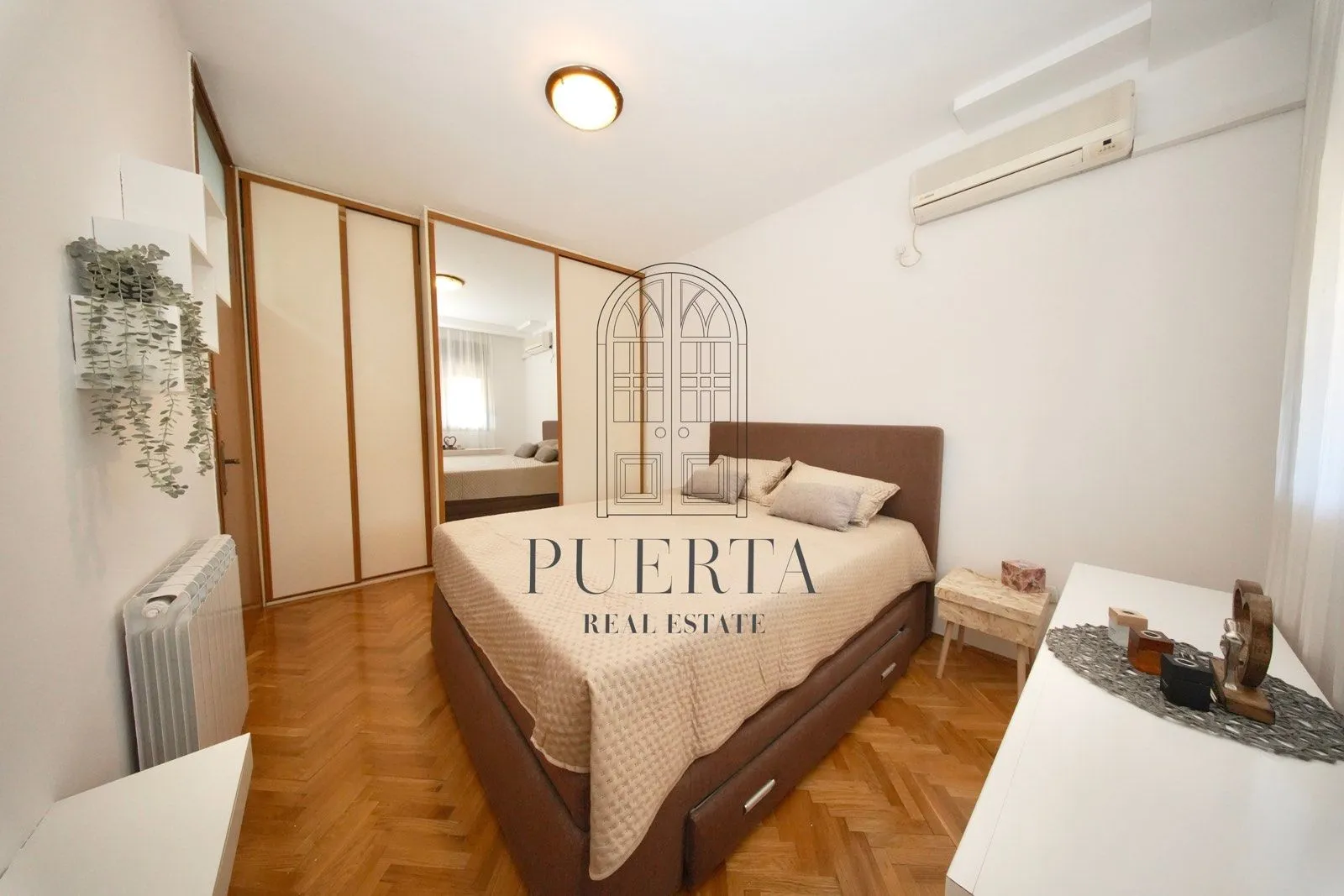 Furnished bedroom with a double bed, wardrobe, and parquet flooring.