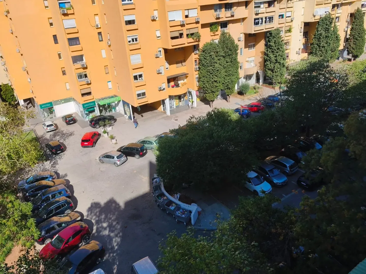 View from the apartment overlooking the residential building and parking lot with greenery.