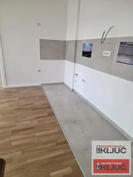 Deo prostora predviđen za kuhinju sa keramičkim pločicama i drvenim podom. - image 3