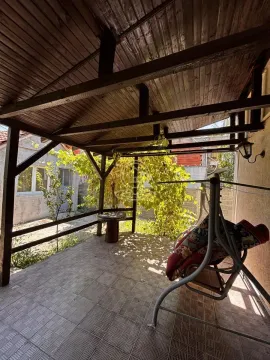 Covered terrace with wooden structure and a swing in the yard. - image 25