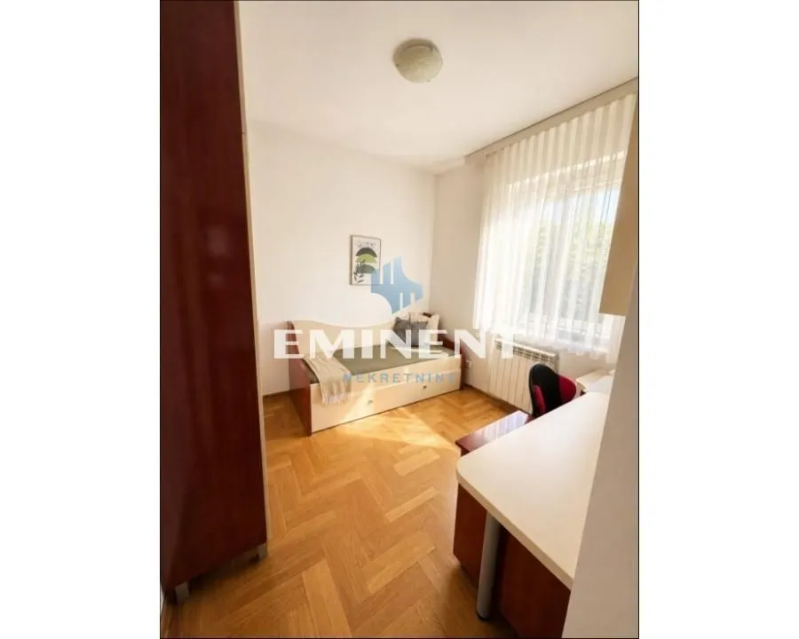 Furnished bedroom with a bed, desk, and a window.