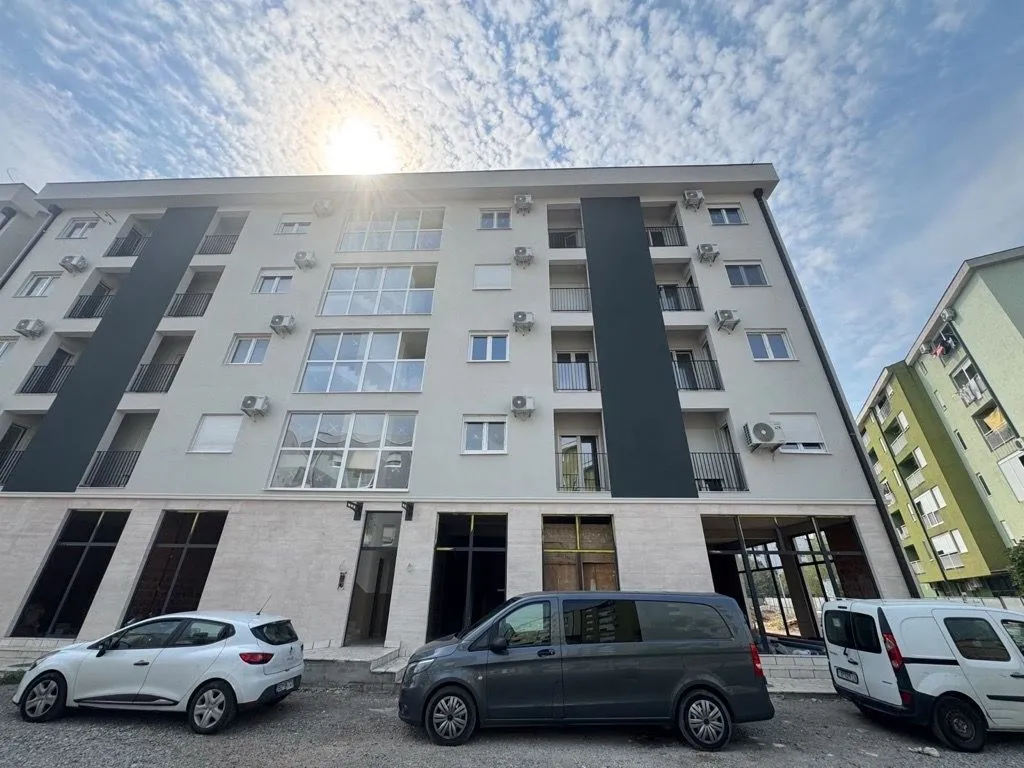 Exterior view of a modern apartment building with parking in front.