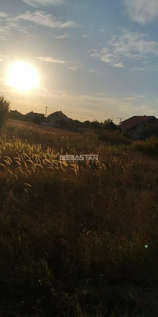 Pogled na plac i okolne kuće u prirodi tokom zalaska sunca.
