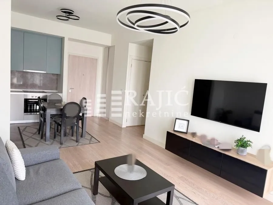 Modern living room with a sofa, TV, and dining area in the background.