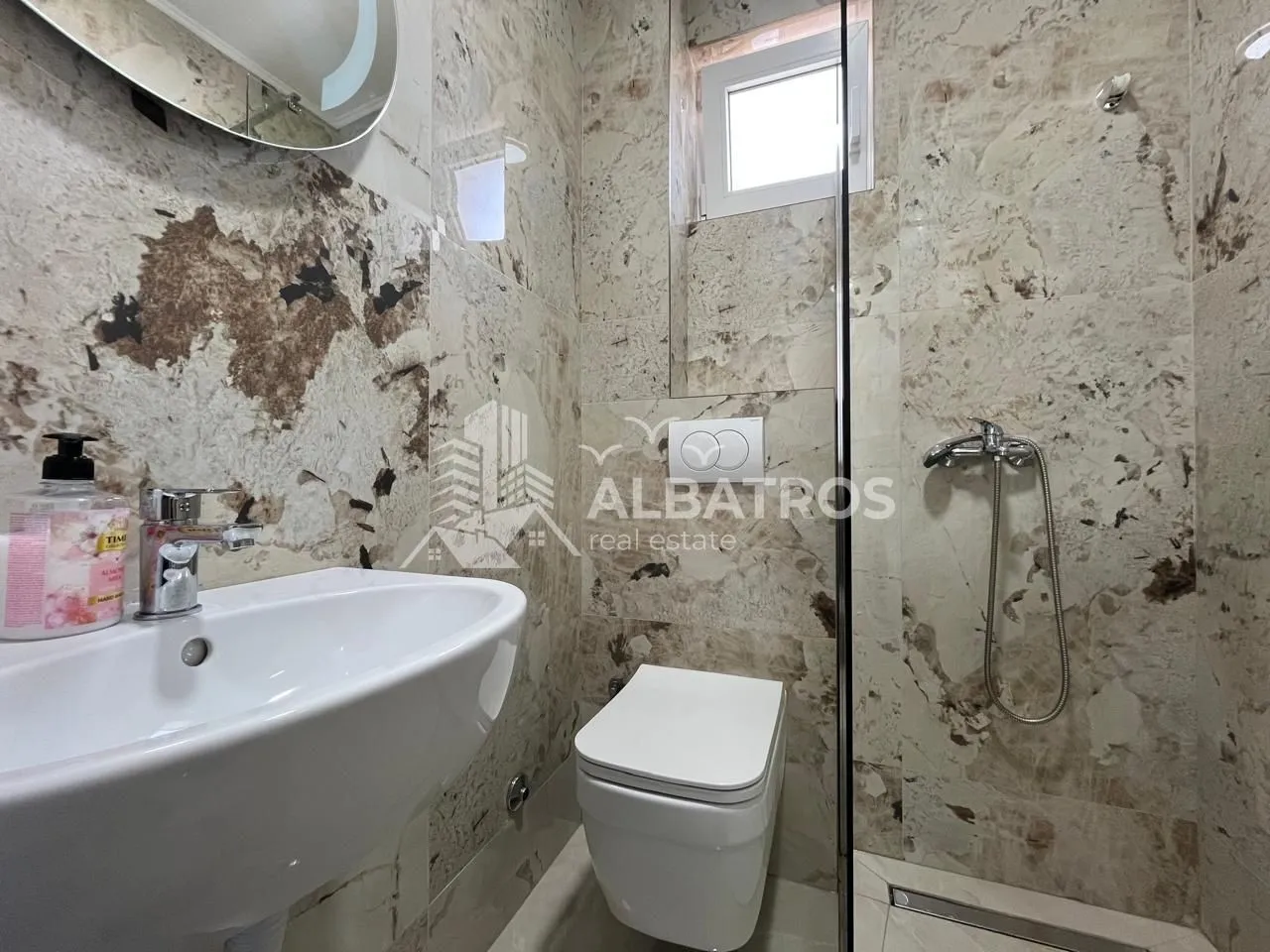 Modernly equipped bathroom with a washbasin, toilet, and walk-in shower.