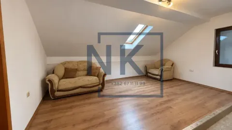 Living room with sloped ceiling, skylight, and sofa. - image 2