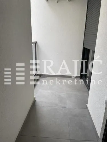 Small enclosed balcony with grey tiles and window shutters.