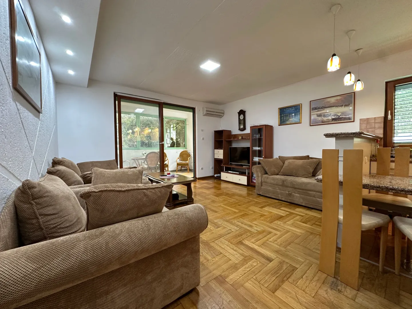 Spacious living room with sofa set and parquet flooring.