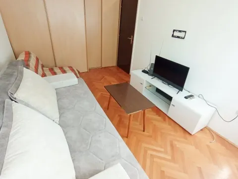 Svijetla dnevna soba sa ugaonim kaučem, drvenim stolom i televizorom. - image 8