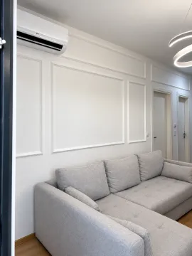 Living room with a grey sectional sofa, white walls with molding, and an air conditioner. - image 11
