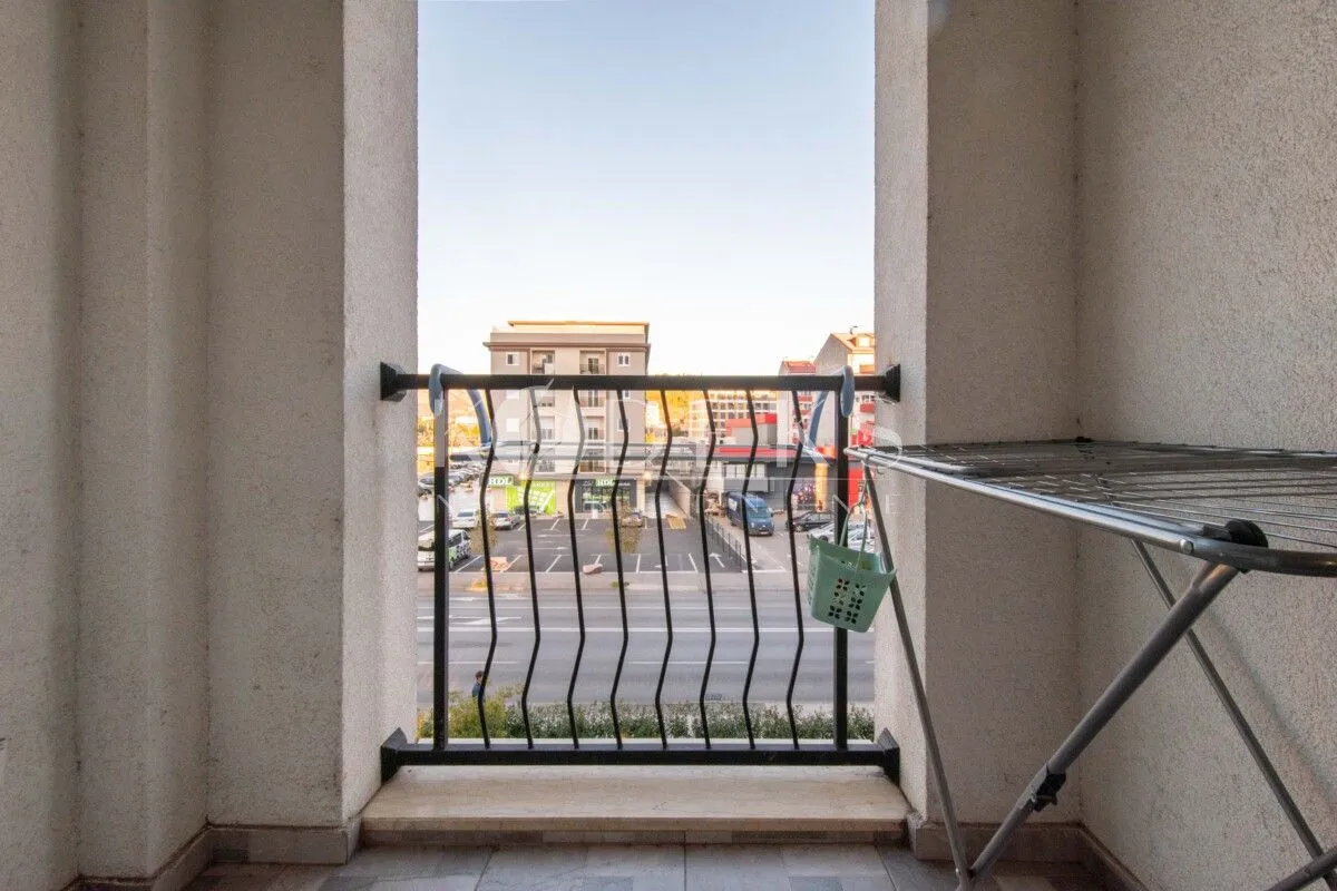 Natkriveni balkon sa metalnom ogradom i pogledom na ulicu.
