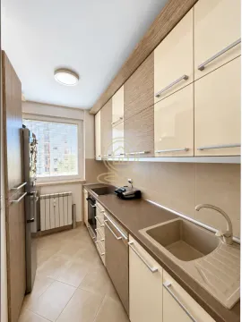 Small narrow kitchen with wooden elements and a window. - image 8