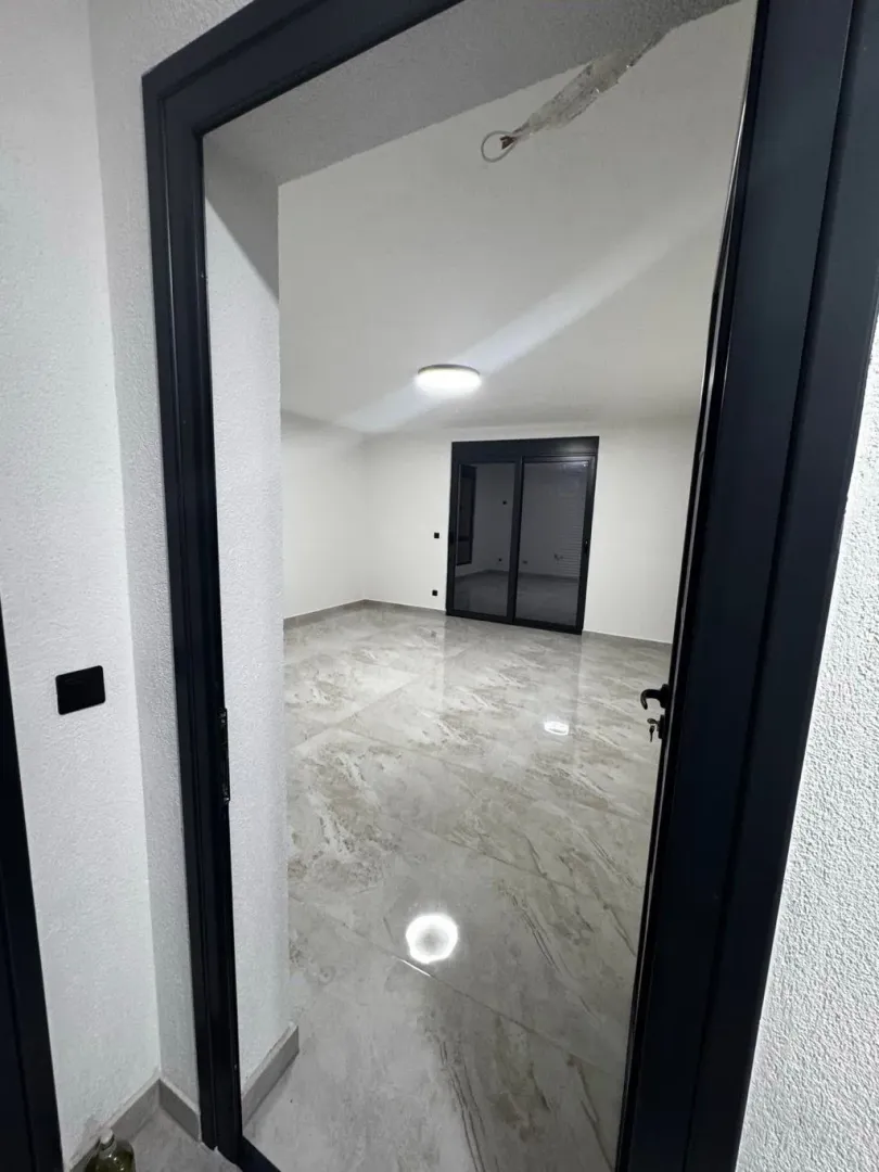 View through a doorway into an empty room with tiled flooring.
