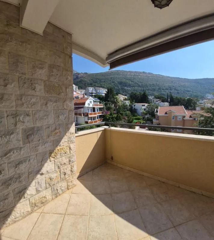 Natkriveni balkon sa pogledom na brda i okolne kuće.