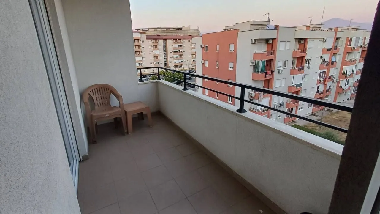 Manji balkon sa plastičnom stolicom i pogledom na okolne zgrade.