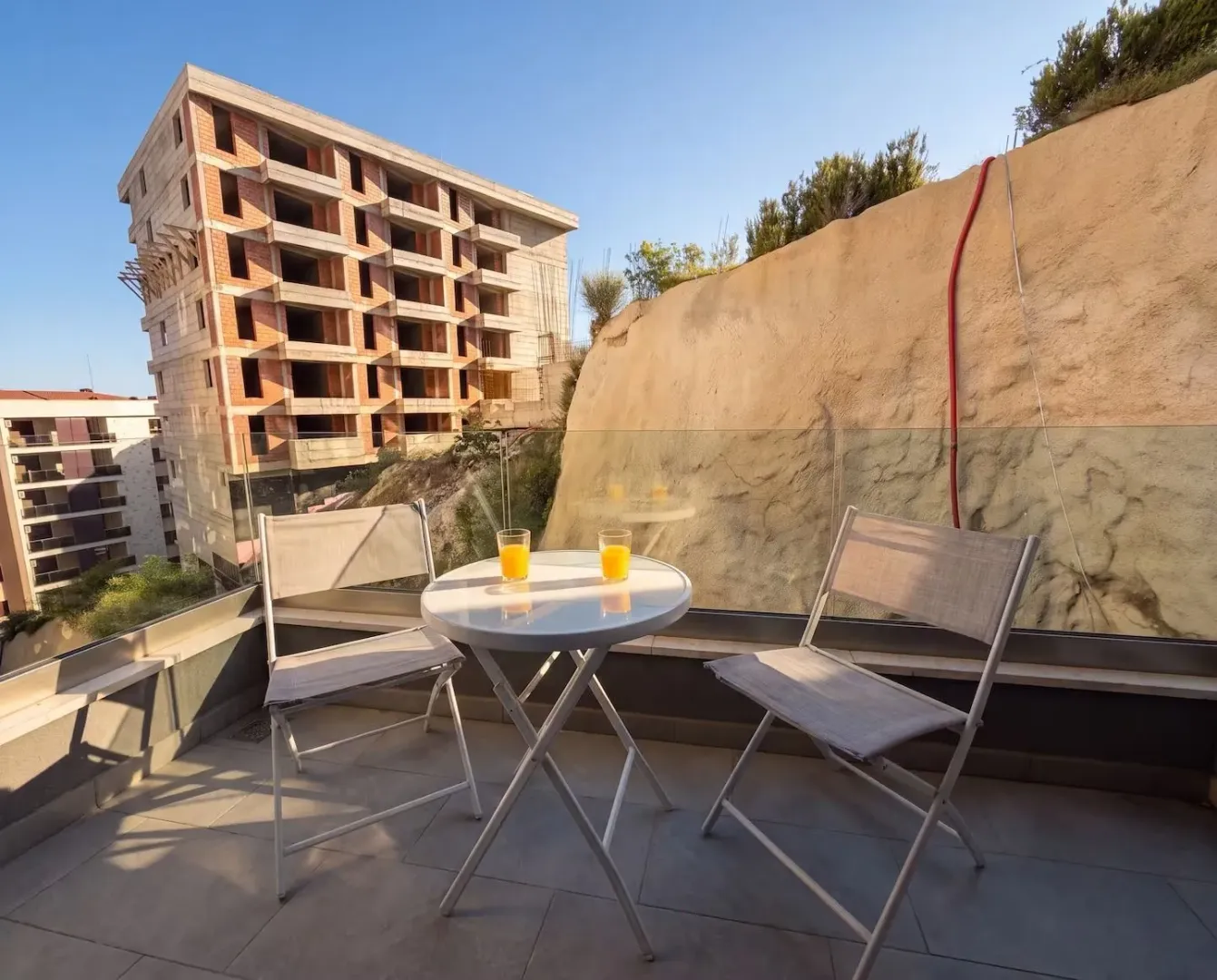 A small table and two chairs on a tiled terrace overlooking surrounding buildings.