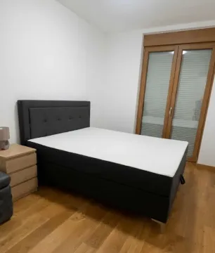 Bedroom with a double bed, wooden floor and balcony doors. - image 4