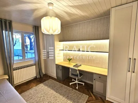 Furnished bedroom with a desk, built-in wardrobes, and wooden flooring. - image 10