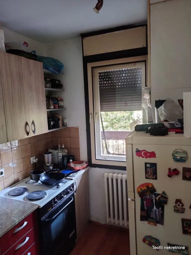 Manja kuhinja sa šporetom, frižiderom i prozorom.