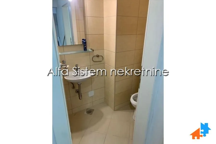 Manje kupatilo obloženo keramičkim pločicama sa umivaonikom i toaletom.