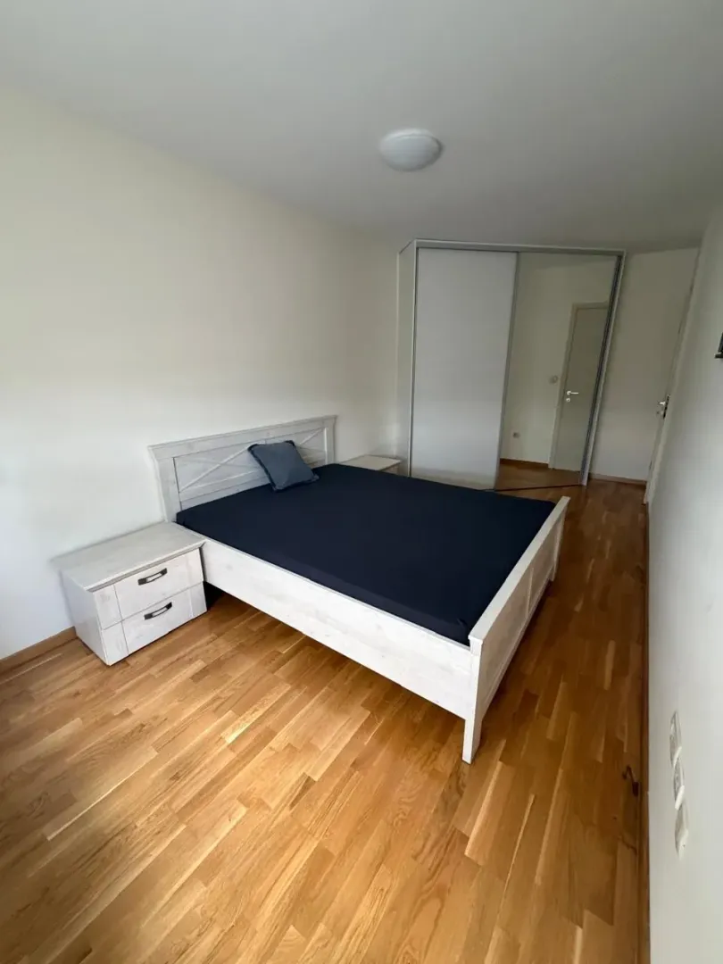 Spavaća soba sa bračnim krevetom, noćnim stočićem i ugradnim plakarom.