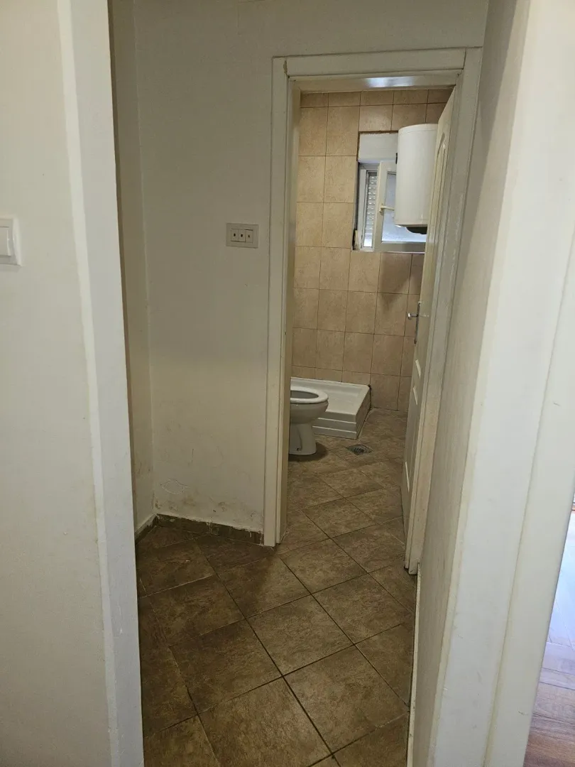 View from the hallway into a tiled bathroom with a shower cabin and toilet.