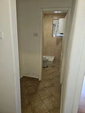 View from the hallway into a tiled bathroom with a shower cabin and toilet. - image 4