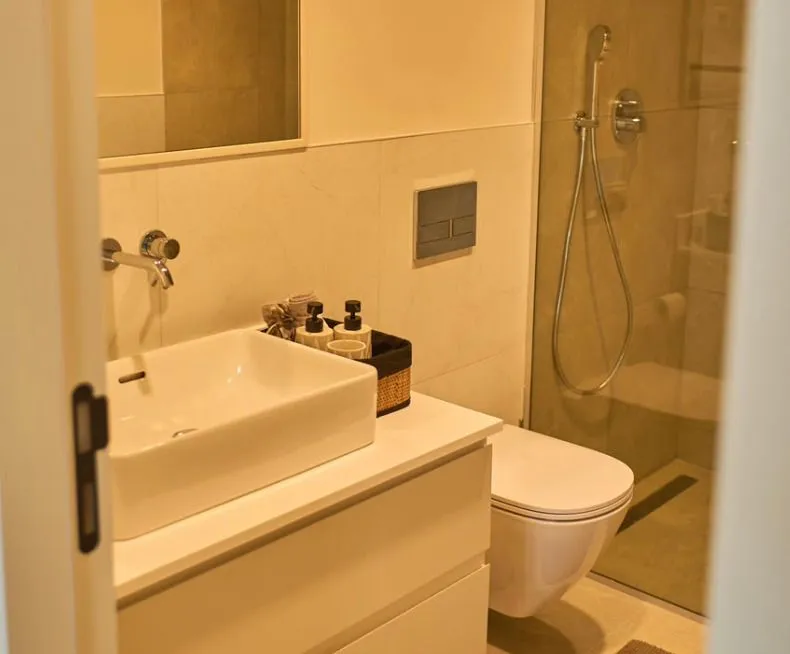 Moderne kupatilo sa umivaonikom, WC šoljom i tuš kabinom.