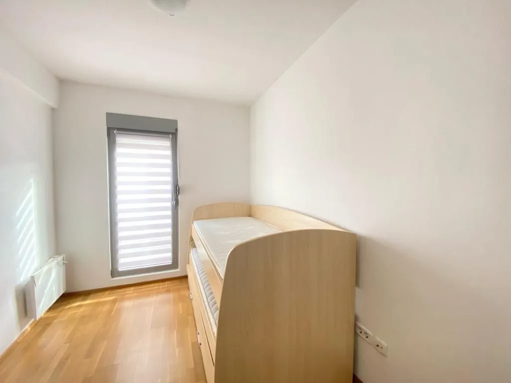 Bright bedroom with a bed and parquet flooring.