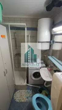 Small bathroom with a shower cabin, washbasin, toilet, and washing machine. - image 10