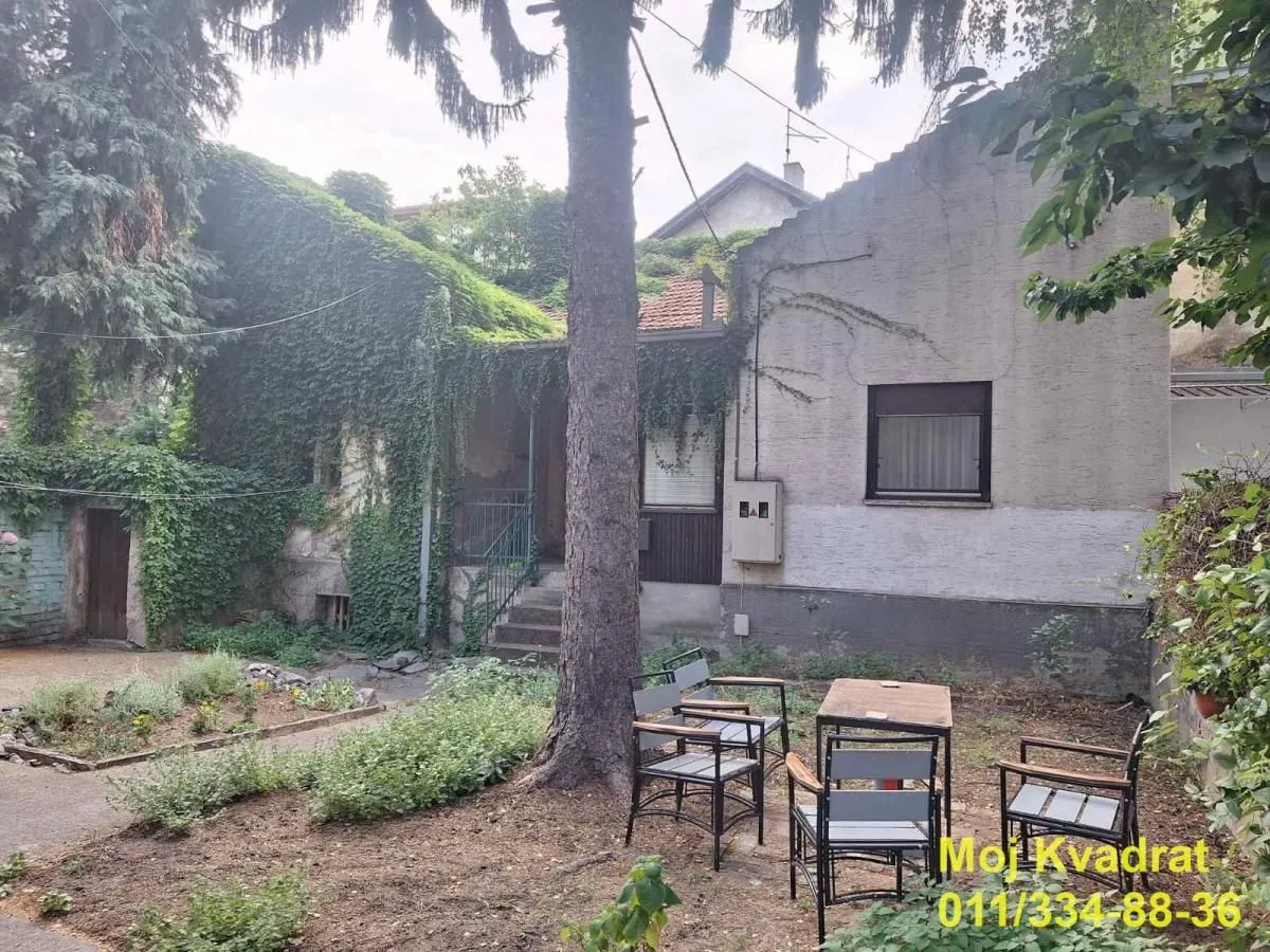 Pogled na dvorište i spoljašnjost kuće sa garniturom za sedenje.