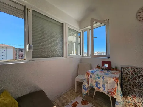 Enclosed balcony with a table, chairs, and a city view. - image 11