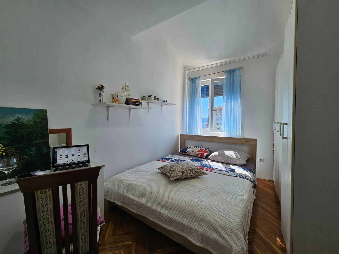 Furnished bedroom with a double bed, wardrobe, and window.