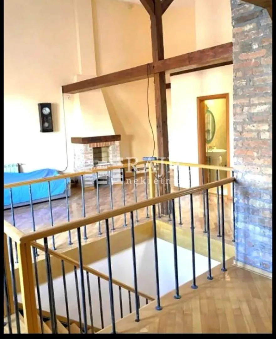 Living room with a gallery and exposed roof beams.