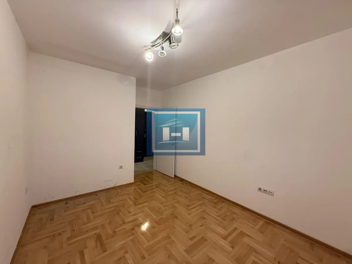 Empty room with hardwood parquet flooring and white walls.