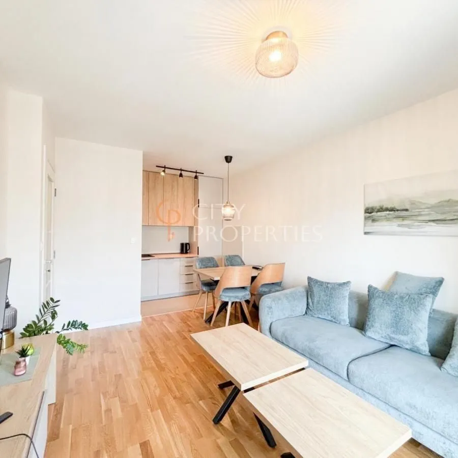 Living room with a sofa, dining area, and kitchen in the background.