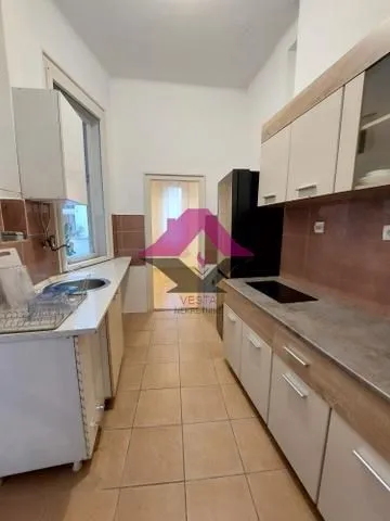 Long kitchen with wooden cabinets, sink, and built-in stovetop.
