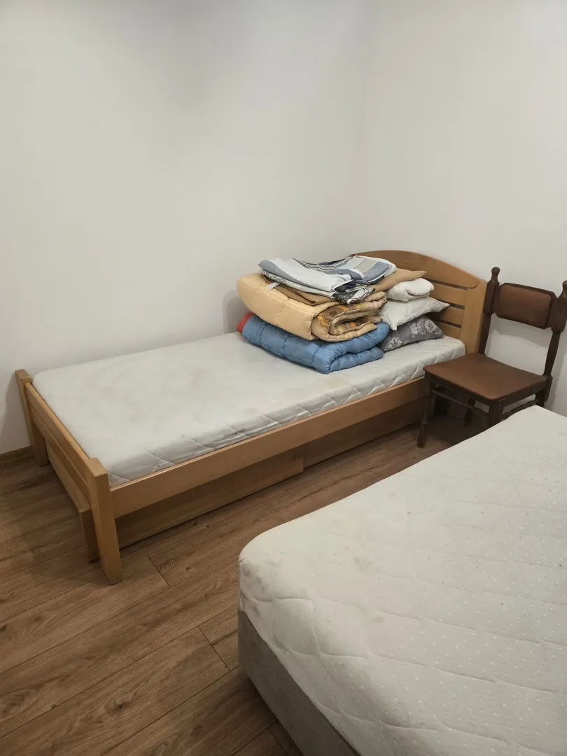 Manja spavaća soba sa dva kreveta i neuređenom posteljinom.
