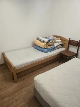 Manja spavaća soba sa dva kreveta i neuređenom posteljinom. - image 6