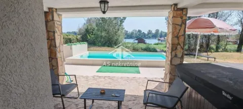 Covered terrace with seating furniture and a view of the pool and river. - image 34