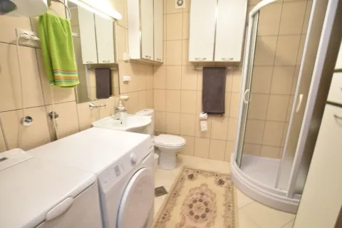 Svijetlo kupatilo sa tuš kabinom, veš mašinom i bež pločicama. - image 18